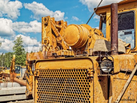 Picture of Old dirty yellow tractor or bulldozer is on the industrial site